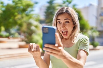 Young woman using smartphone with cheerful expression at park