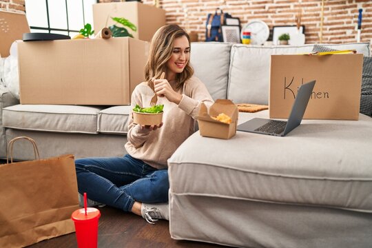 Young woman eating delivery food watching movie at new home
