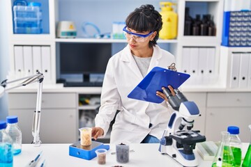 Young woman scientist measuring liquid at laboratory