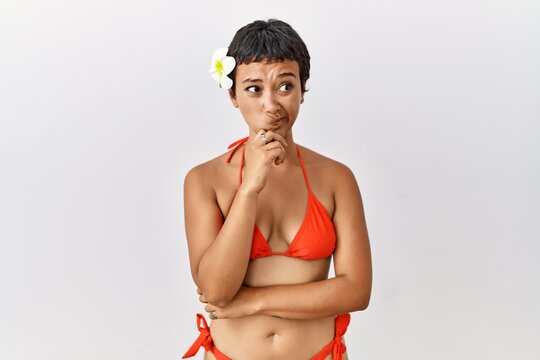 Young hispanic woman with short hair wearing bikini thinking worried about a question, concerned and nervous with hand on chin