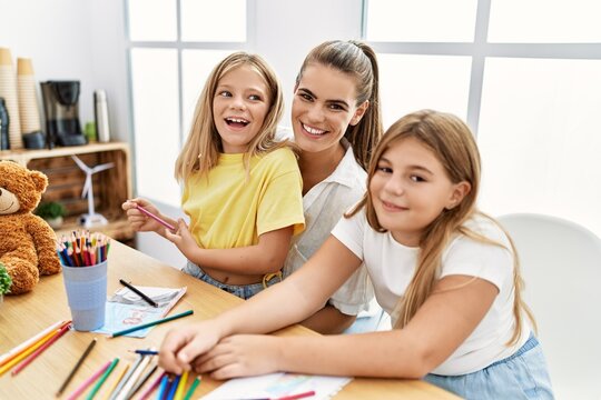 Mother and daughters smiling confident drawing at home