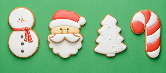 Tasty Christmas cookies on green background, top view