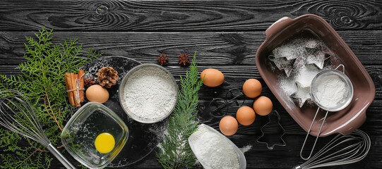 Ingredients for Christmas bakery and kitchen utensils on dark wooden background