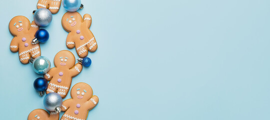 Tasty gingerbread cookies and Christmas decor on light blue background with space for text