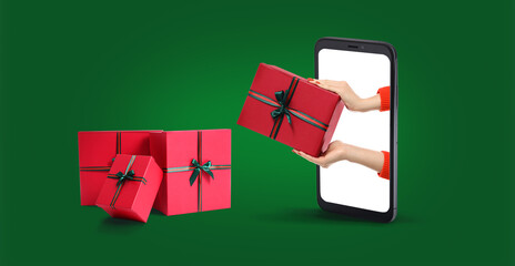 Mobile phone with female hands on screen and gifts on green background