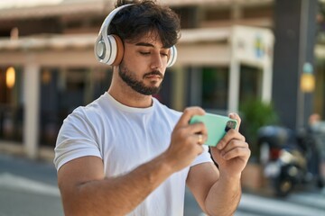 Young hispanic man playing video game at street