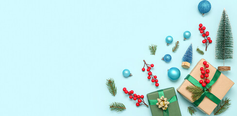 Christmas gift boxes with fir branches and decor on light blue background with space for text, top view