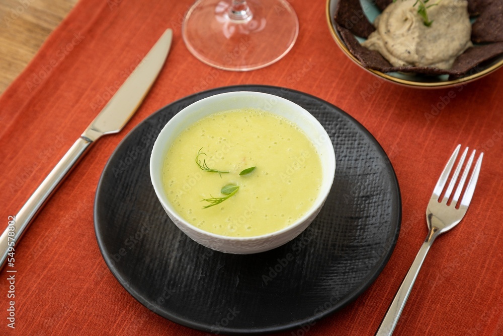 Sticker closeup of a creamy fennel soup served in a bowl on a red tablecloth