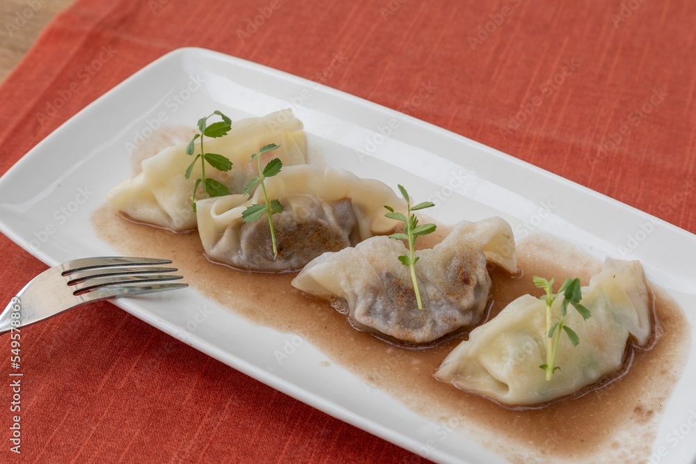 Sticker Closeup of stuffed dumplings served in a rectangular white plate on a red tablecloth