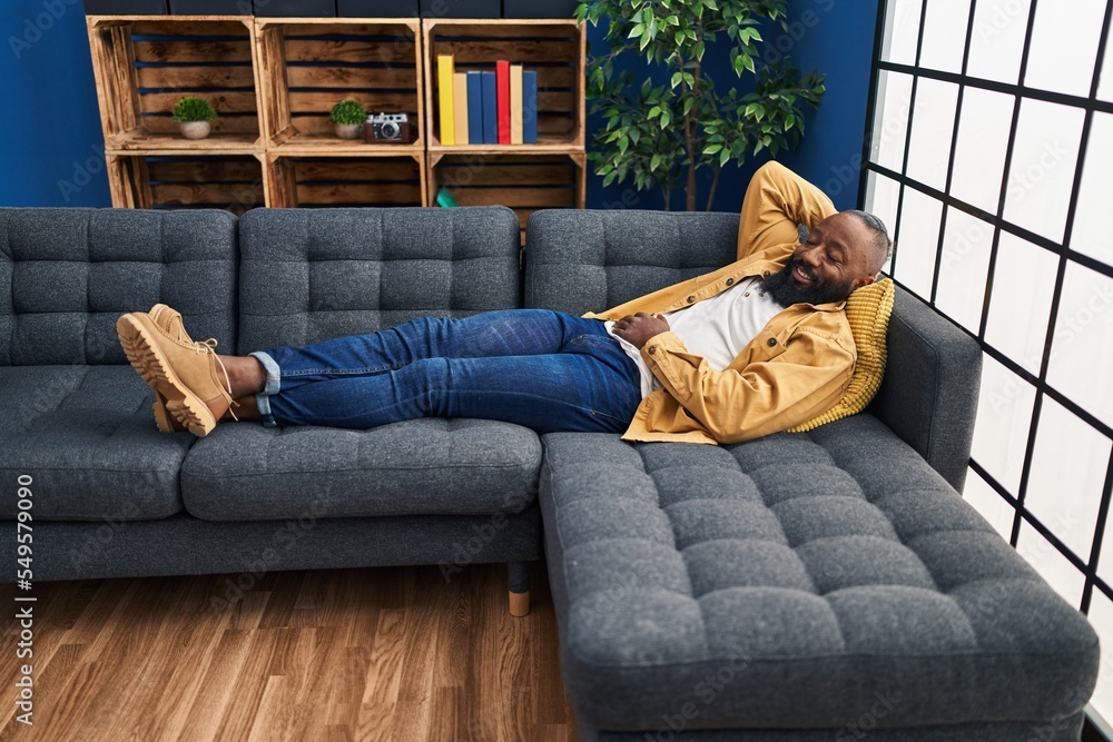 Canvas Prints young african american man smiling confident relaxed lying on sofa at home