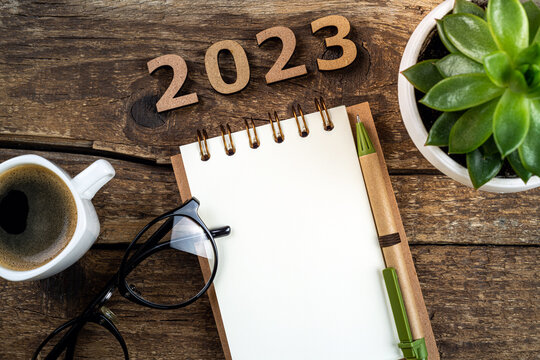 New year resolutions 2023 on desk. Wooden eco friendly reusable new year decorations 2023, notebook, coffee cup on table. Goals, resolutions, plan, sustainable concept. New Year 2023 background