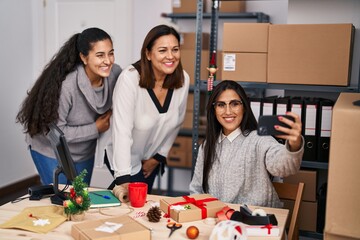 Fototapeta premium Three woman ecommerce business workers making selfie by smartphone at office