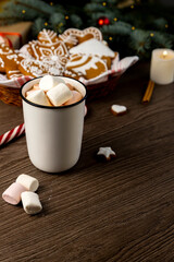 Greeting Christmas card. Gingerbread cookies, cocoa with marshmallows and a candle on the table. Focus on the cup.