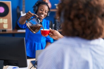 African american women musicians smiling confident drinking coffee at music studio