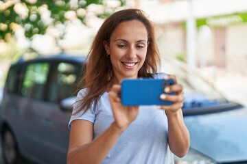 Young woman smiling confident using smartphone at street