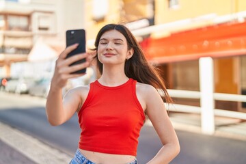 Young caucasian woman smiling confident making selfie by the smartphone at street