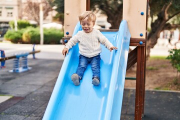 Fototapeta na wymiar Adorable toddler playing on slide at park