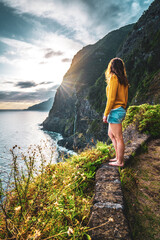 Sporty woman looking at waterfall flowing into the sea in atmospheric morning atmosphere. Viewpoint...