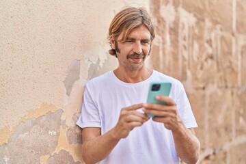 Fototapeta premium Young blond man using smartphone at street
