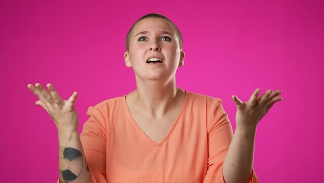 Angry, scared young gender fluid non binary woman 20s put hands on head screaming crying ask why me, isolated on pink background studio. Slow motion