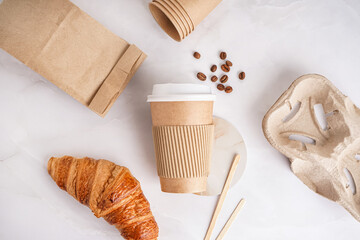 Paper cup, bag, holder and croissant on light background