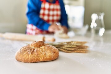 Senior man keading dough with hands at kitchen