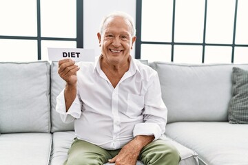 Senior man holding diet banner looking positive and happy standing and smiling with a confident smile showing teeth