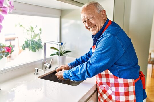 Senior Man Smiling Confident Washing Hands At Kitchen