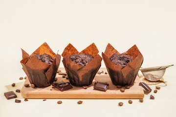 Wooden board with tasty chocolate muffins on color background