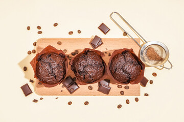 Wooden board with tasty chocolate muffins on color background