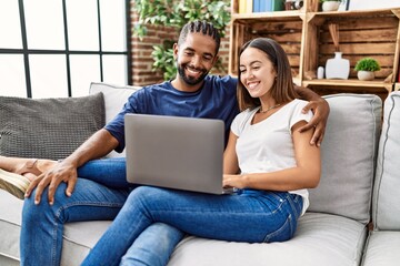 Man and woman couple using laptop hugging each other at home