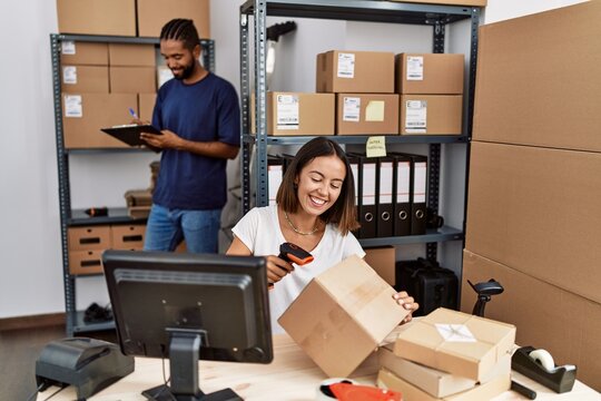 Man and woman business partners scanning package using barcode reader at storehouse