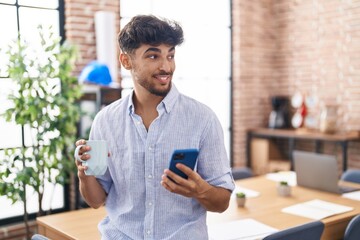 Young arab man business worker using smartphone drinking coffee at office