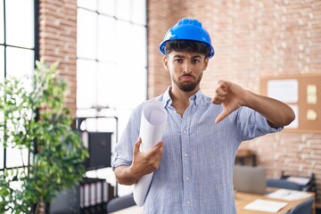 Arab man with beard wearing architect hardhat at construction office with angry face, negative sign showing dislike with thumbs down, rejection concept