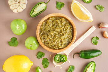 Composition with bowl of tasty green salsa sauce and ingredients on color background