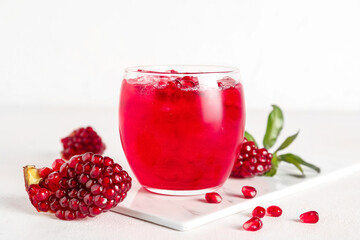 Glass of cold pomegranate juice on light background