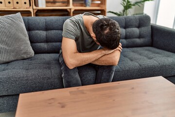 Young hispanic man psychology patient depressed sitting on sofa at clinic