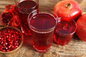 Glasses of tasty pomegranate juice and fresh fruits on wooden table, closeup