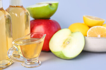 Gravy boat with apple cider vinegar on light background, closeup