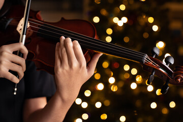 Teen playing violin in formal wear on christmas background © Kenishirotie