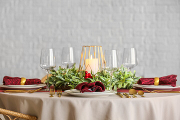 Christmas table setting with mistletoe wreath near white brick wall