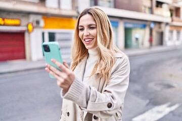 Fototapeta premium Young blonde woman smiling confident having video call at street