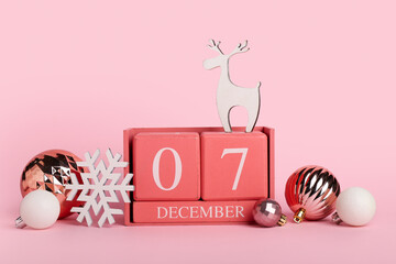 Cube calendar with date 7 DECEMBER and Christmas decor on pink background