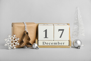 Cube calendar with date 17 DECEMBER, Christmas decor and gift on light background