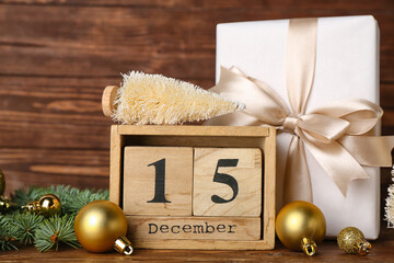 Cube calendar with date 15 DECEMBER, Christmas decor and gift on wooden background