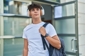 Young hispanic teenager student smiling confident listening to music at university