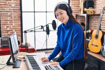 Chinese woman musician composing song at music studio - obrazy, fototapety, plakaty