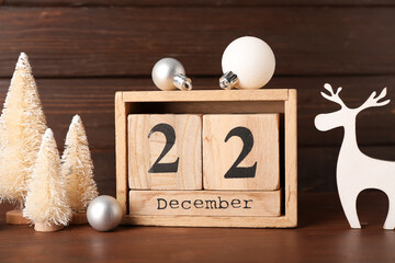 Cube calendar with date 22 DECEMBER and Christmas decor on dark wooden background