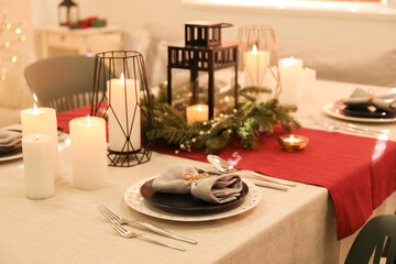 Christmas table setting with wreath and burning candles in dining room