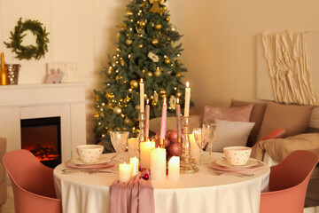 Christmas table setting with burning candles and balls in dining room